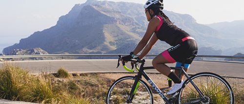 Mulher pedalando em estrada em treinamento de ciclismo para mulheres