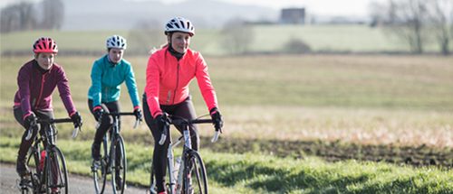 Mulheres em grupo pedalando estrada em alimentação do ciclista Alimentação para treinos de ciclismo com mulhere pedalando em estrada 