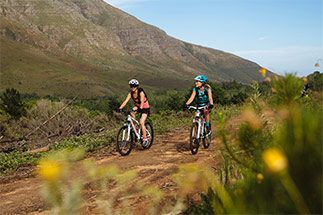 Duas mulheres pedalam em meio a montanhas com a calibragem correta do pneu da bicicleta