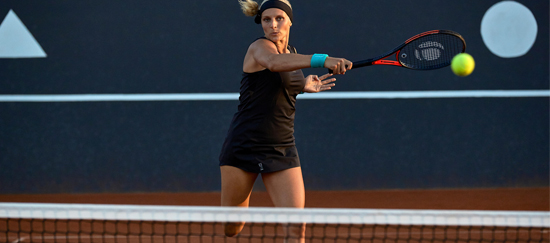 Mulher jogando tênis em quadra de saibro