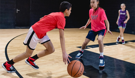 Disputa de bola entre um menino e uma menina na quadra de basquete